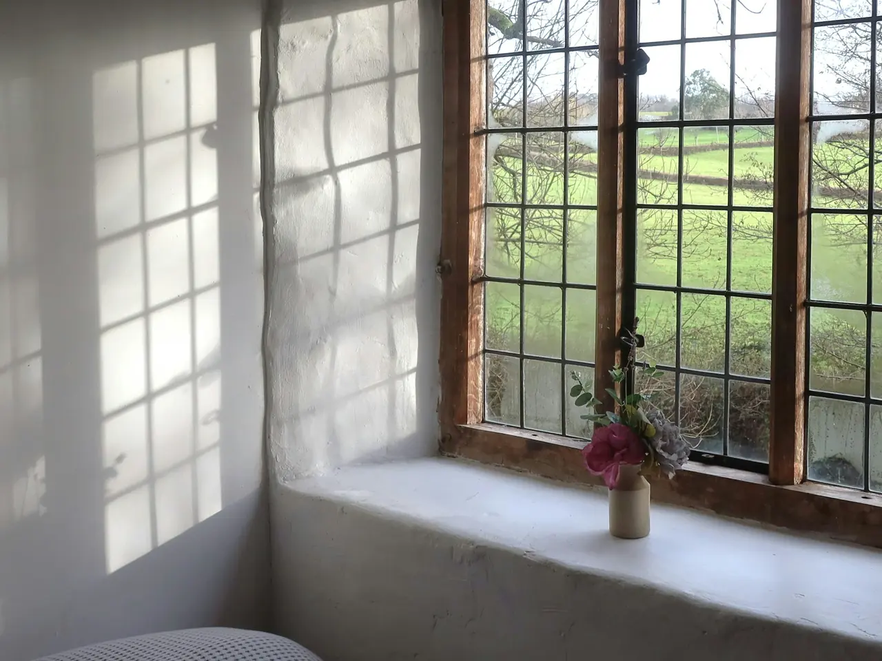 Jarrón con flores en el alféizar de una ventana