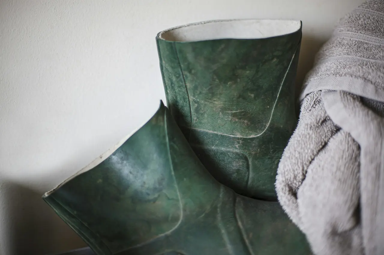 Botas de agua verdes y una toalla
