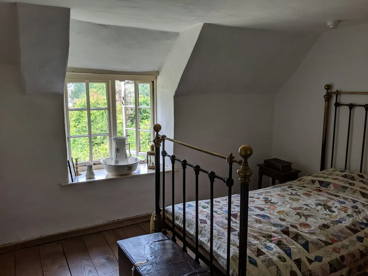 Dormitorio con cama de hierro antigua y ventana pequeña