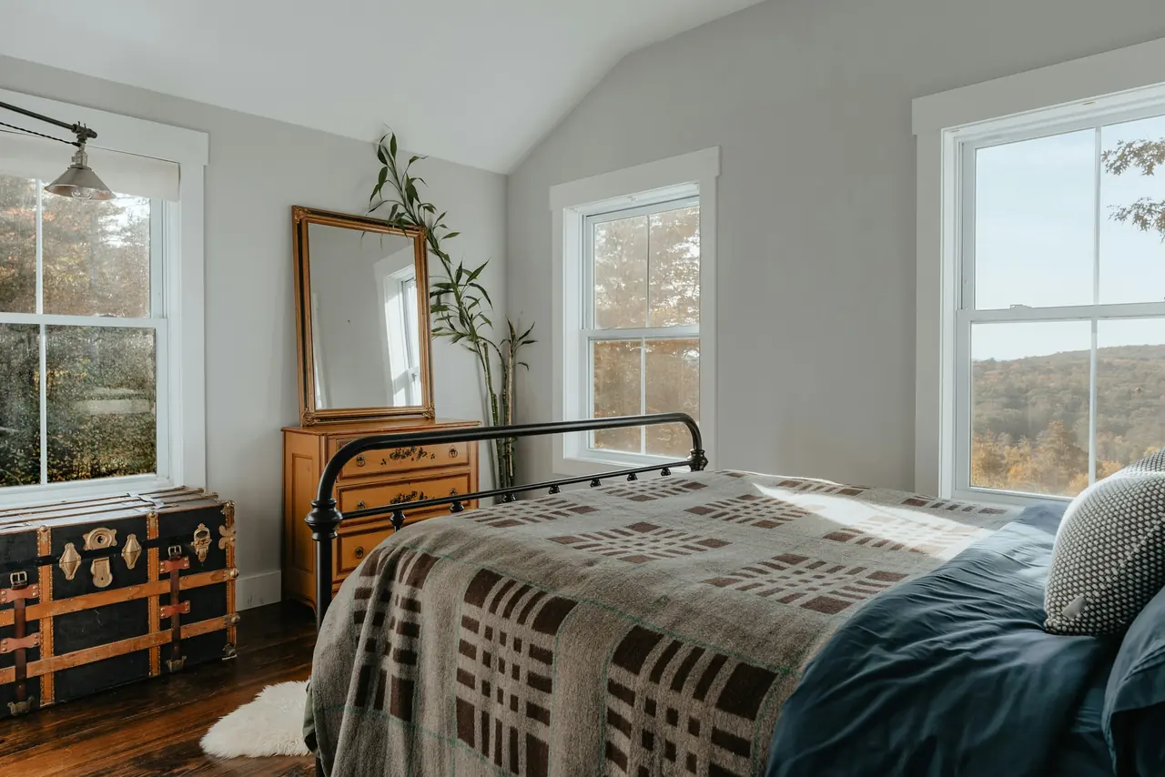 Cama con manta de lana junto a una ventana