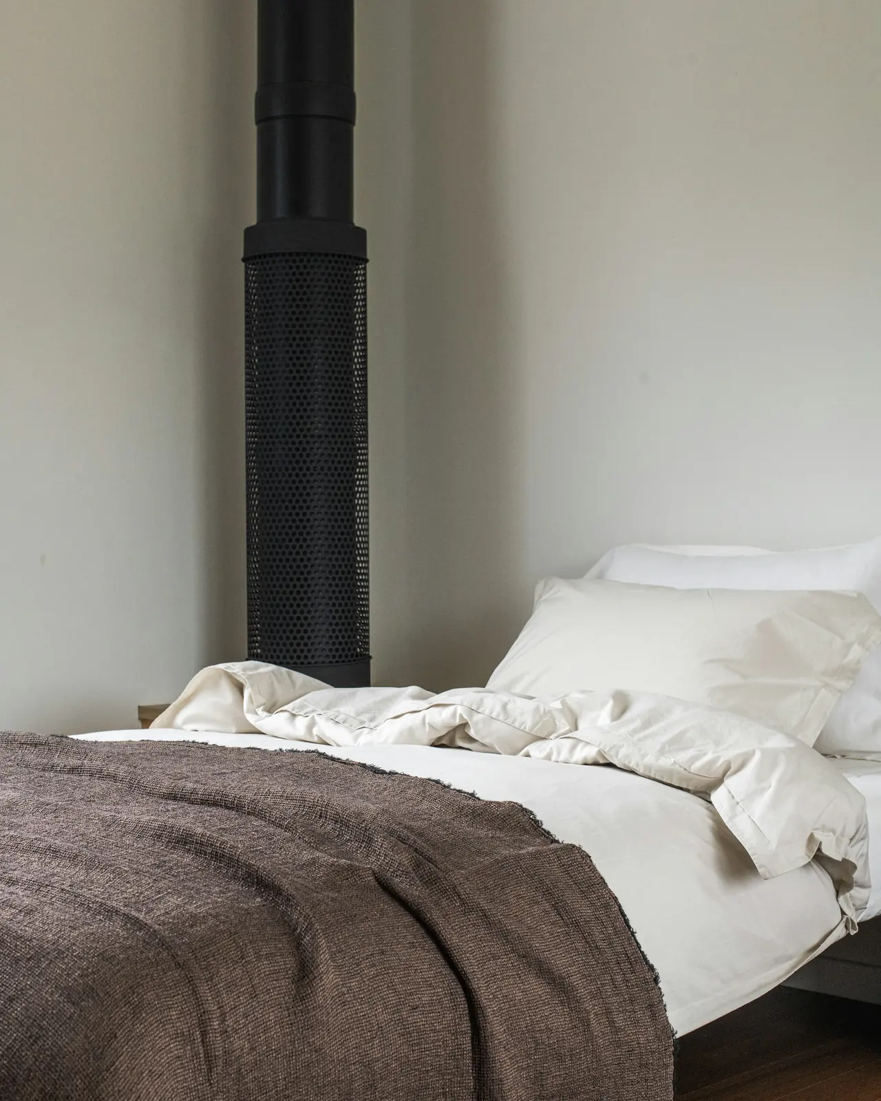Cama hecha con una manta de lana marrón