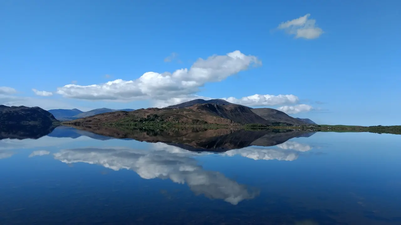 El lago Caragh en primavera, quieto, con las colinas reflejadas