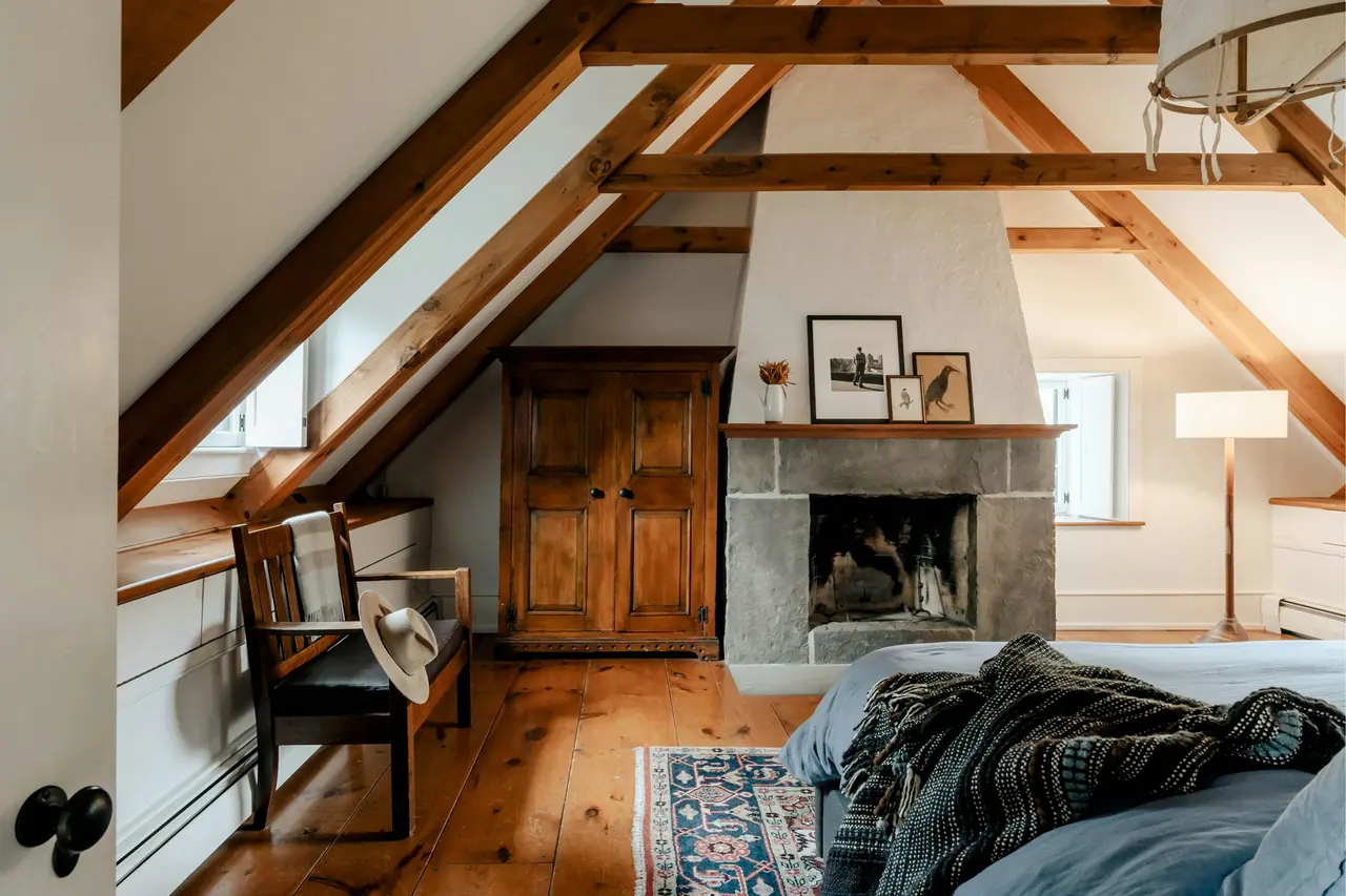 Attic room with wooden beams, a fireplace and a bed